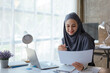 © aksonsat - Muslim business woman working on laptop with happy and smile face on office spec.