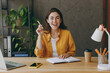 © ViDi Studio - Young creative proactive successful employee business woman 20s she wear casual yellow shirt holding pen with great new idea sit work at wooden office desk with pc laptop. Achievement career concept.