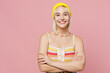 © ViDi Studio - Young fun blond lesbian woman 20s she wear colorful knitted top yellow hat hold hands crossed folded look camera isolated on plain pastel light pink background. People lgbtq lifestyle fashion concept.