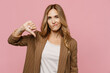 Young displeased disappointed sad employee business woman 30s she wearing casual brown classic jacket showing thumb down dislike gesture isolated on plain pastel light pink background studio portrait.