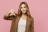 Fototapeta  - Young displeased disappointed sad employee business woman 30s she wearing casual brown classic jacket showing thumb down dislike gesture isolated on plain pastel light pink background studio portrait.