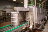 Fototapeta  - Brewery, bottling beer on aluminum kegs on conveyor lines. Industrial work, automated modern food and beverage production.
