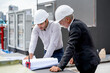 © narong - Close up shot young and senior engineer man work together using building plan or drawing in workplace of construction site.