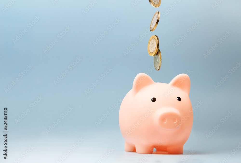 Pink piggy bank with falling coins on blue background Stock Photo ...