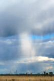 Fototapeta Tęcza - Imposing storm cloud discharging water over a field. Vertical format.