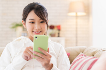 Wall Mural - 部屋でスマホを見る女性