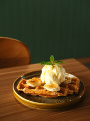 Caramelized Croissant Waffle or Croffle with banana slice and ice cream topping, served on brown plate
