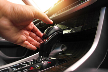 The driver hand is putting the gear lever to change the automatic gear position in the car.