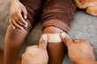 © Kay Abrahams/peopleimages.com - Parent childcare, knee injury and plaster on child leg after getting hurt showing care, love and support to help growth and childhood development. Hands closeup of adult applying bandage to kid