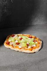 Sticker - Italian pizza with chicken and tomatoes on dark background. A-la Caesar pinsa on gray stone table with hard shadow. Roman pizza with chicken and caesar sauce on concrete background. Pinsa menu.