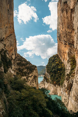 Blue sky with clouds between narrow rocky cliffs. River in Congost de Mont Rebei gorge in Catalonia, Spain. Natural border between Catalonia and Aragon.