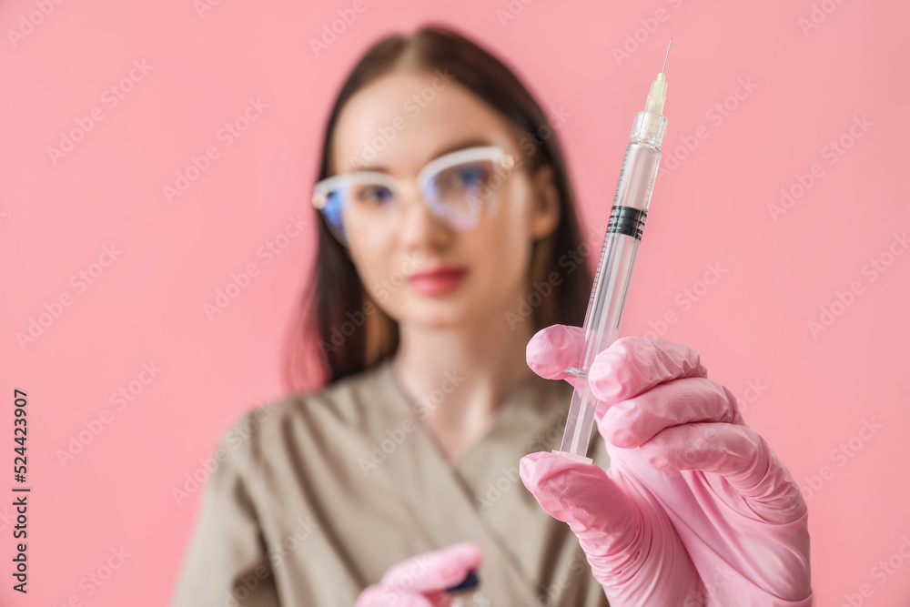 Doctor with syringe on pink background, closeup