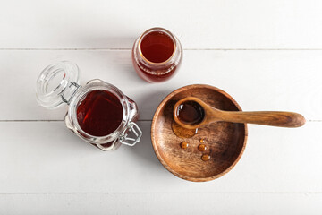Wall Mural - Jar, bottle and spoon with tasty maple syrup on light wooden background