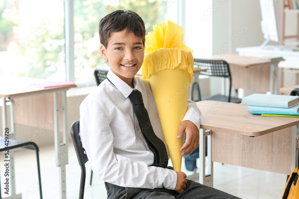 Little boy with yellow school cone in classroom