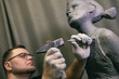 © primipil - Man sculptor creates sculpt bust human woman sculpture with hammer. Statue craft creation workshop.