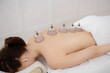 Young pretty woman having back massage with vacuum cups in spa, white background. Copy space, closeup