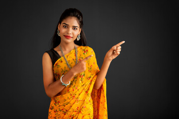 Poster - Portrait of a successful cheerful young girl pointing and presenting something with hand or finger with a happy smiling face.