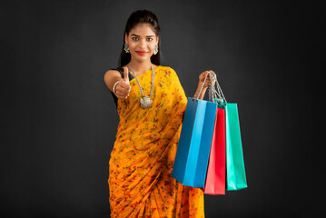 Sticker - Beautiful Indian young girl holding and posing with shopping bags on a grey background