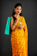 Sticker - Beautiful Indian young girl holding and posing with shopping bags on a grey background