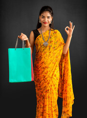 Sticker - Beautiful Indian young girl holding and posing with shopping bags on a grey background