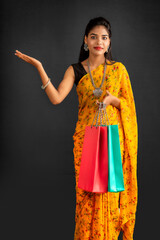 Sticker - Beautiful Indian young girl holding and posing with shopping bags on a grey background