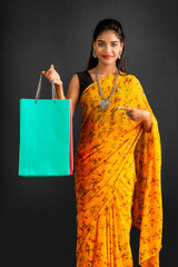 Wall Mural - Beautiful Indian young girl holding and posing with shopping bags on a grey background