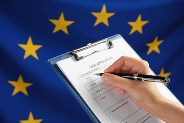 Wall Mural - Woman filling visa application form against flag of European Union, closeup