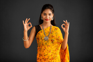 Poster - Young smiling girl showing ok sign or thumbs up on a grey background