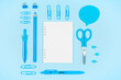 Blue school supplies and blank notepad on blue background