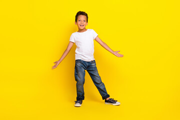 full size photo of little boy stand wear t-shirt jeans shoes isolated on yellow color background
