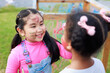 Happiness Asian girl painting Affican girl face. Diverse happiness kid group playing in playground at summer camp learning