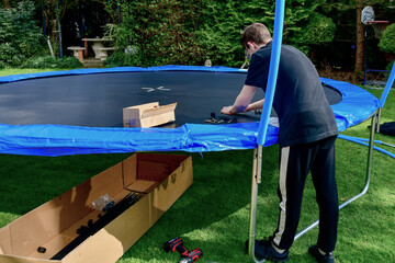 Children collect a disassembled trampoline in the yard after purchase.