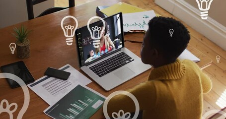 Sticker - Animation of floating bulbs over african american woman having video call on laptop