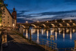 Steinerne Brücke nachts beleuchtet mit Spiegelung in Regensburg mit Brückturm