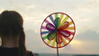 happy child with spinner toy sunset background. girl childhood dream. child park with windmill. pinwheel child hand outdoors. color pinwheel concept. small child park plays spinner toy. happy family.