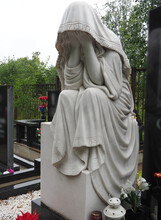 Weeping Woman. Sculpture In The Cemetery. The Figure Of A Mother, Wife Or Woman In A Hood Or Stole. Lamentation For The Deceased. Tombstone On A Christian Grave. Sadness And Grief
