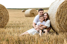 Young Family Mom Dad And Son On The Field Near The Straw Bales. Family Photo Session