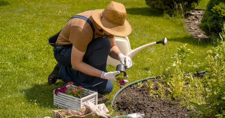 Wall Mural - young man in a straw hat and hands in gloves is engaged in gardening work,