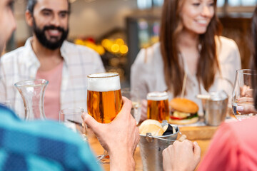 Canvas Print - leisure, eating, food and drinks, people and holidays concept - close up of happy friends having dinner and drinking beer at restaurant or pub