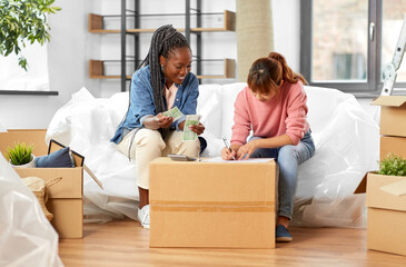 Sticker - moving, finances and real estate concept - happy smiling women with money, bills and calculator at new home