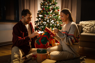 Canvas Print - holidays, celebration and people concept - happy couple opening christmas gifts at home