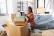 © Syda Productions - moving, people and real estate concept - happy smiling woman packing boxes sitting on sofa at home