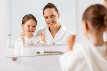 Sticker - beauty, hygiene, morning and people concept - happy smiling mother and little daughter with dental floss cleaning teeth and looking to mirror at bathroom