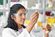 © Syda Productions - science research, work and people concept - female scientist in goggles with dropper and chemical or test sample in beaker working in laboratory