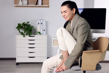 Poster - Young woman rubbing sore foot in office. Space for text