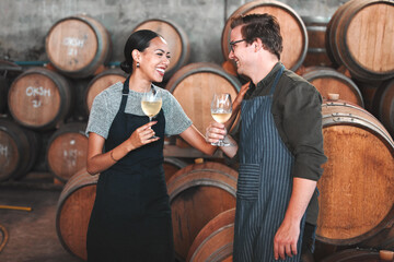 Winemaker business partners having fun talking at winery, white wine tasting and laugh. Young sommelier testing flavor and alcohol drink blend, bonding in cellar, celebrating good quality Chardonnay