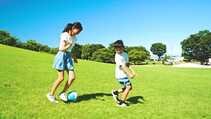 Wall Mural - 青空の公園でサッカーをするアジア人の子供