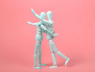 Wall Mural - Two hugging wooden puppets on a pink background. Love, romantic concept