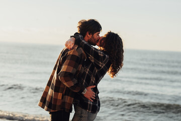 Woman and man hugging and kissing with sea on the background, young couple fall in love