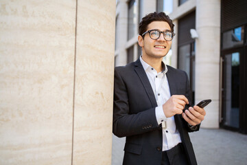 Wall Mural - A male manager uses a phone message app, goes to work in a new office in a suit